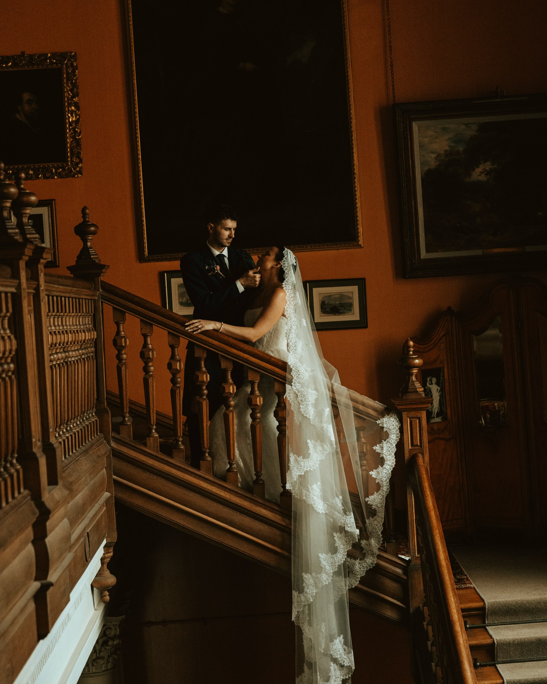 Bride and groom holding each other on a staircase landing