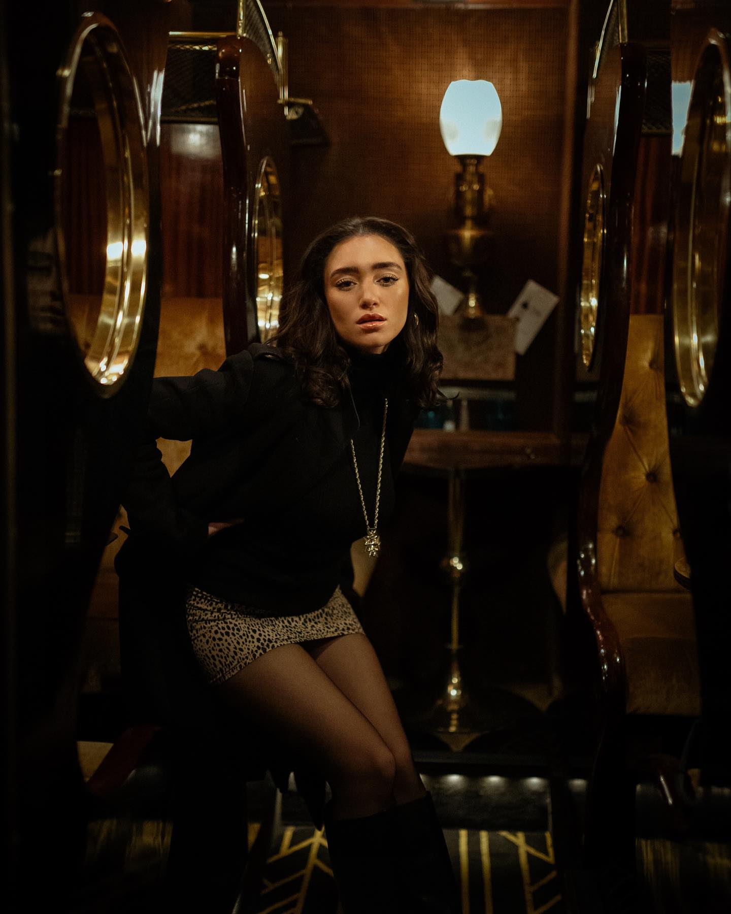 Editorial portrait in a dark brass and velvet lounge
