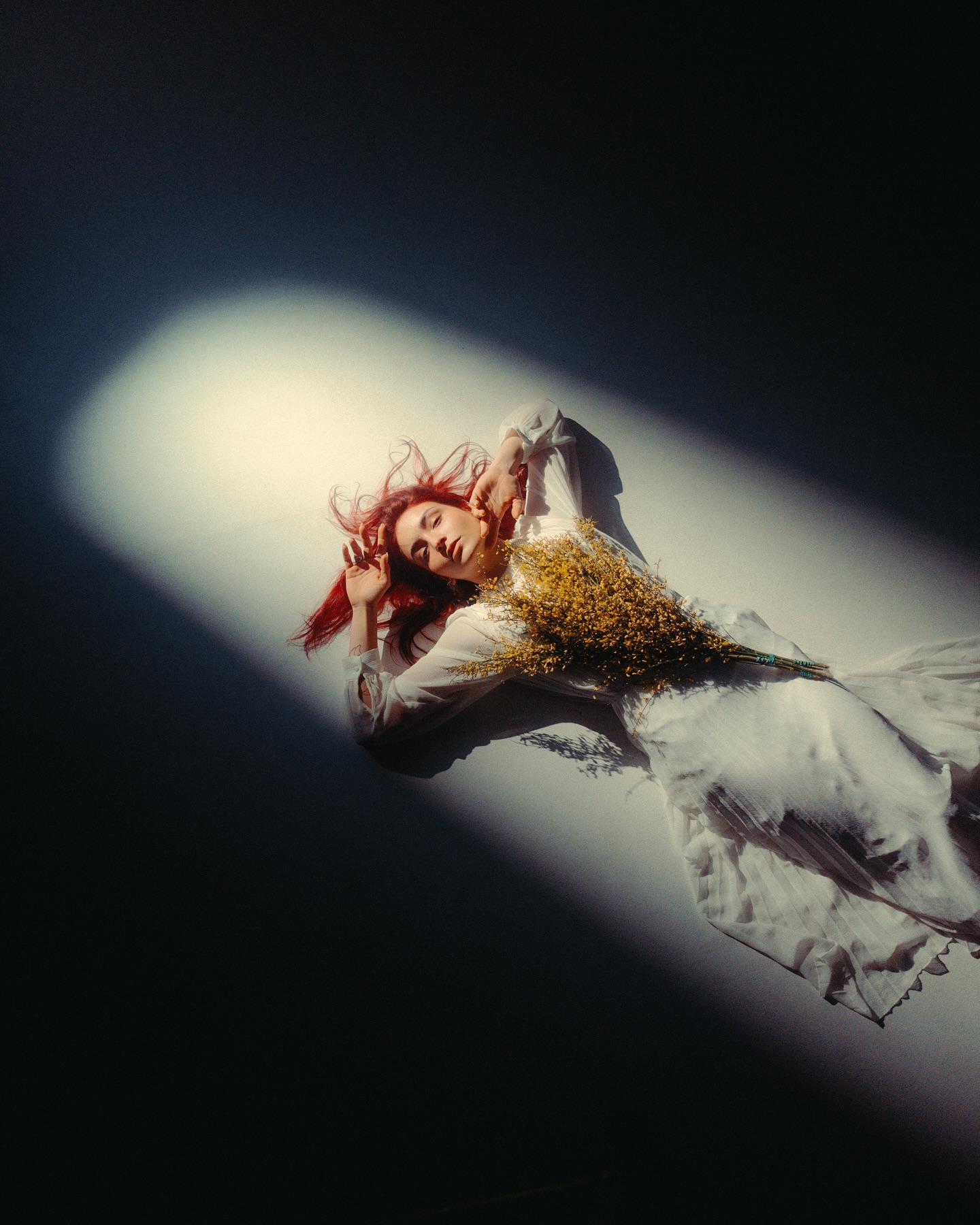 Portrait lying in a hard beam of light with dried flowers