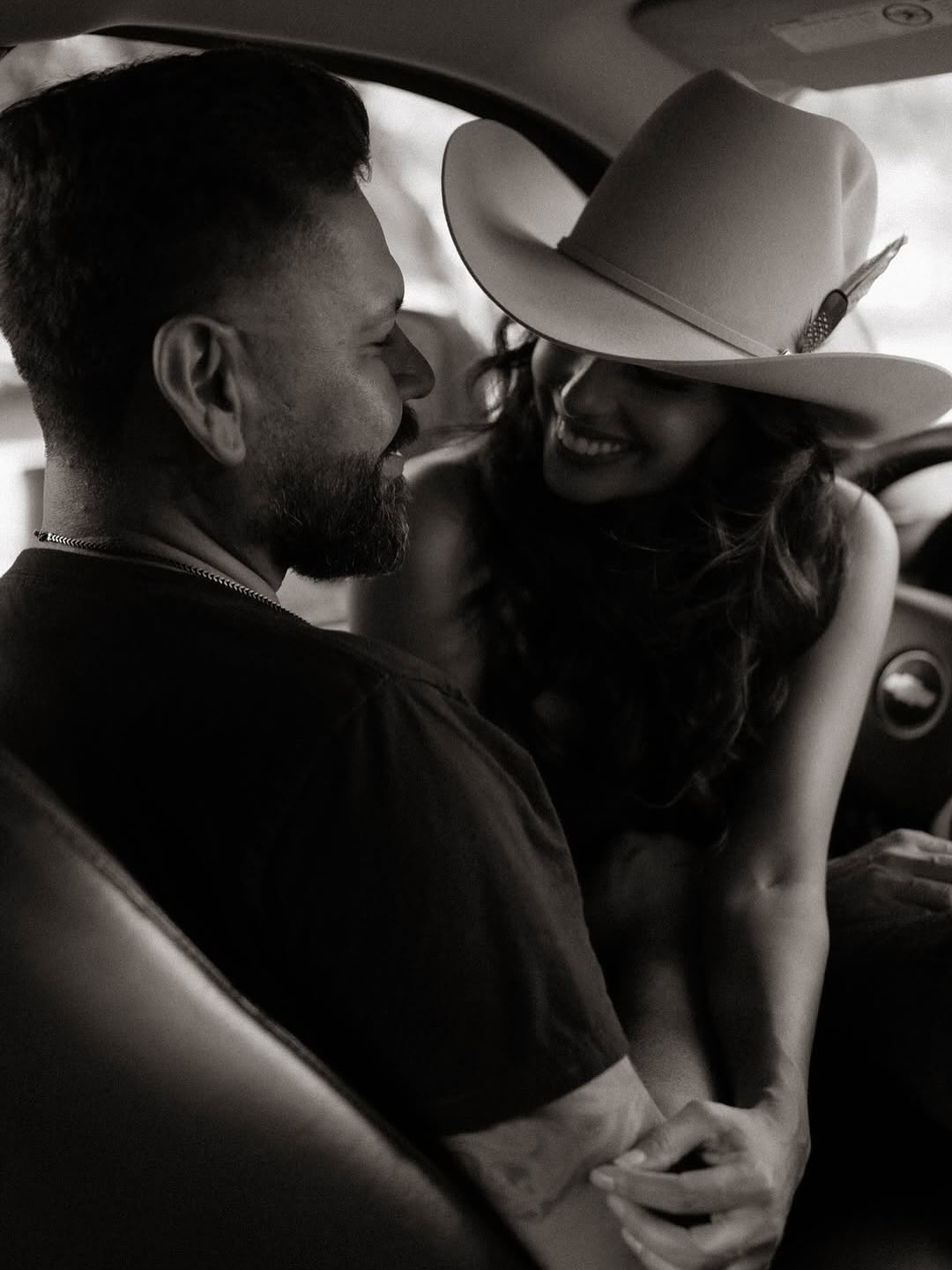 Black and white portrait of a couple laughing inside a truck