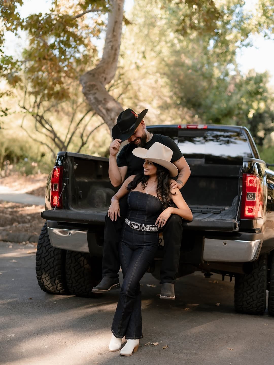 Couple in cowboy hats leaning against a truck tailgate